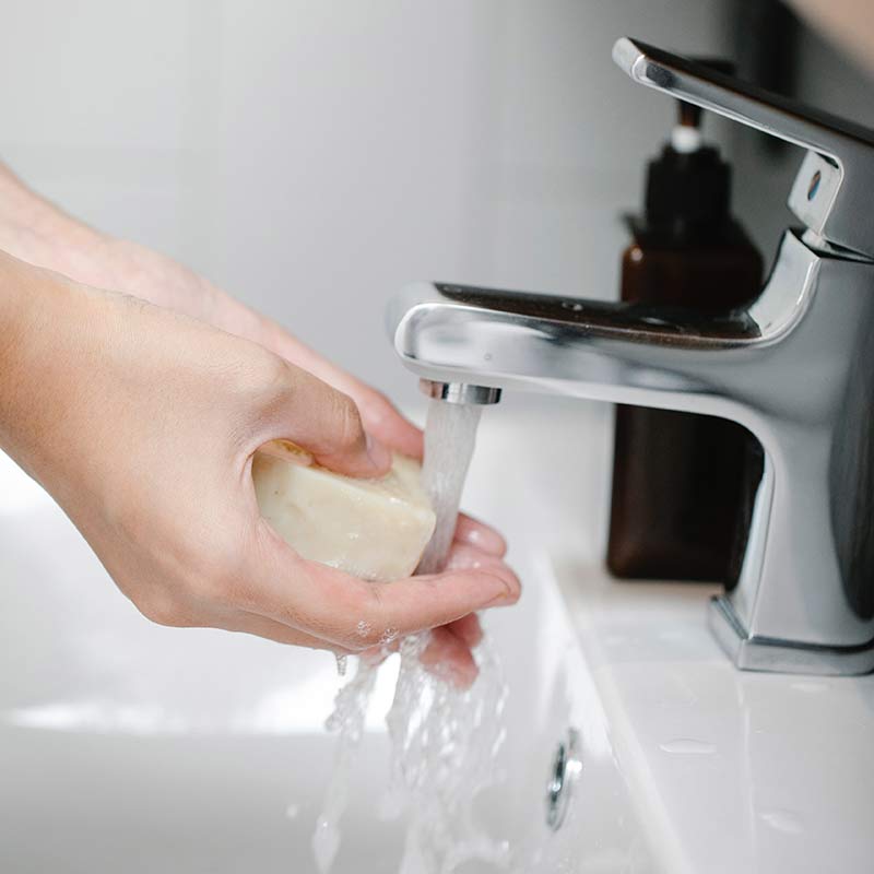 Hands being washed with soap under a tap